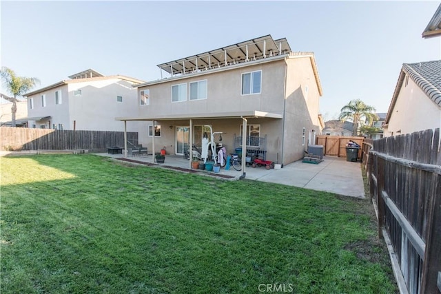 back of house featuring a yard, a fenced backyard, a patio, and stucco siding