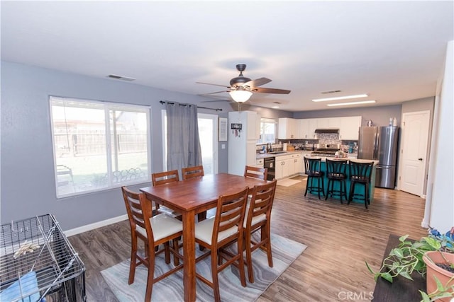 dining space featuring light wood-style floors, visible vents, baseboards, and a ceiling fan