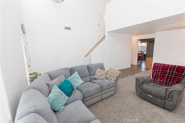 living area featuring a towering ceiling, stairs, wood finished floors, and visible vents