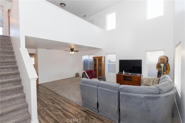 living area featuring a high ceiling, stairway, wood finished floors, and a ceiling fan