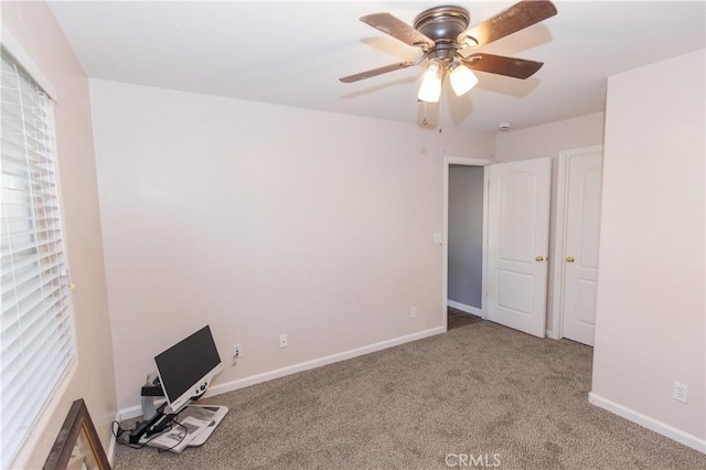 carpeted empty room with ceiling fan and baseboards