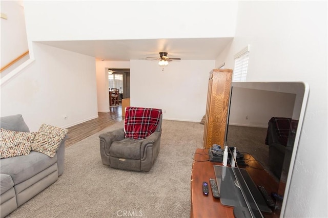 carpeted living area featuring ceiling fan and baseboards