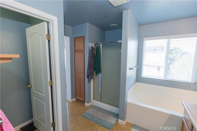 full bath featuring a garden tub, a shower stall, and baseboards