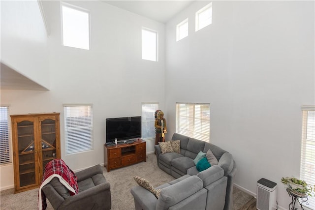 living area featuring light colored carpet, a towering ceiling, and baseboards