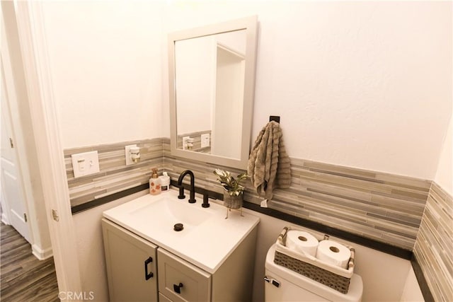 bathroom with toilet, tile walls, and vanity