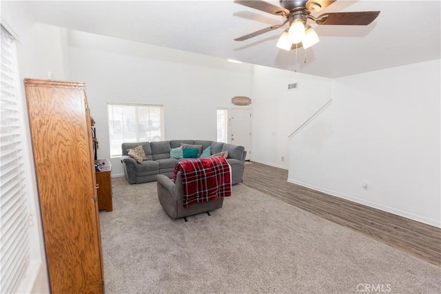 living area featuring visible vents, ceiling fan, baseboards, and wood finished floors