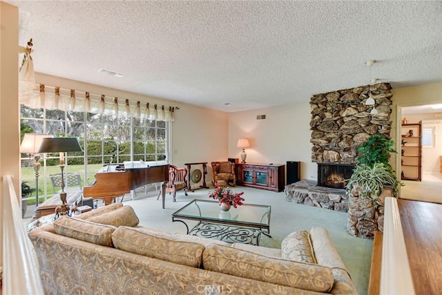 carpeted living room with visible vents, a textured ceiling, and a stone fireplace