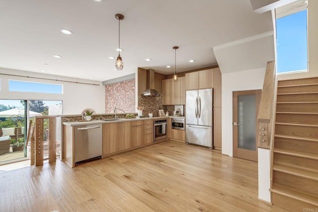 kitchen featuring light brown cabinets, appliances with stainless steel finishes, wall chimney exhaust hood, light wood finished floors, and modern cabinets