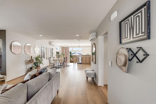 living area featuring light wood finished floors, a wall mounted air conditioner, and recessed lighting