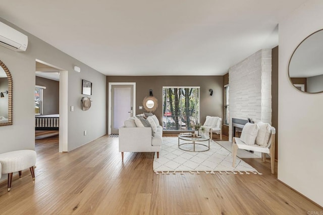 living area with a large fireplace, light wood finished floors, and a wall mounted AC