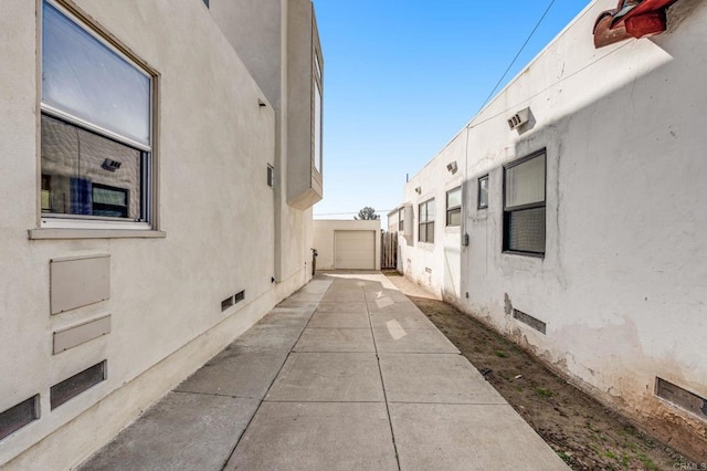 view of side of property with driveway, a garage, crawl space, fence, and stucco siding