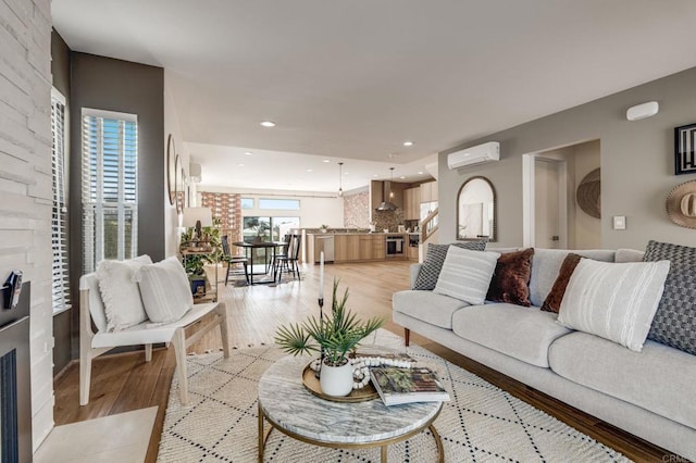 living room featuring light wood finished floors, a wall mounted AC, and recessed lighting