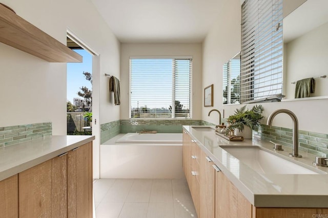 full bathroom with double vanity, decorative backsplash, a garden tub, tile patterned flooring, and a sink