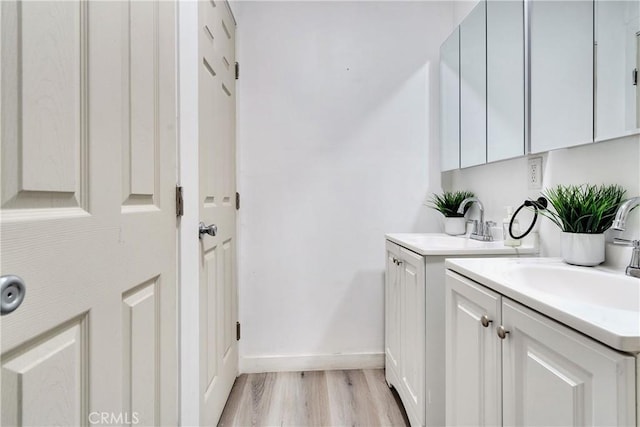 laundry room featuring light wood-type flooring, baseboards, and a sink