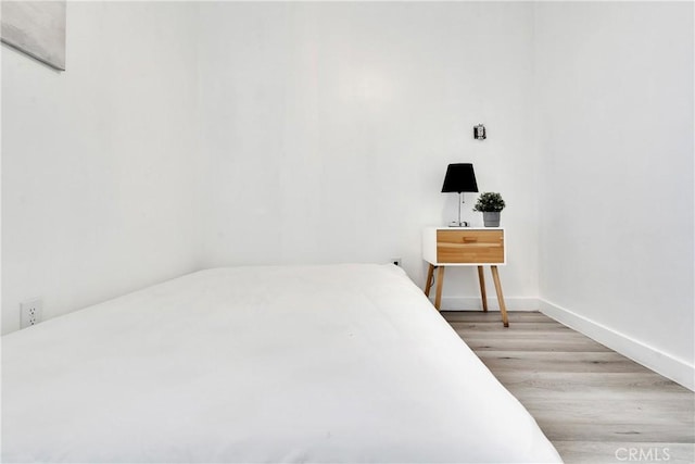 bedroom with light wood-type flooring and baseboards