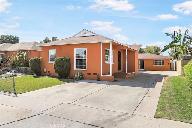 view of front facade with fence, driveway, a front lawn, and stucco siding