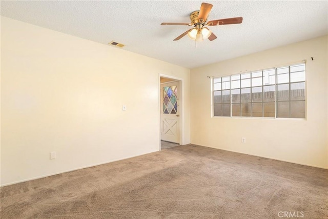 carpeted spare room featuring a textured ceiling, ceiling fan, and visible vents