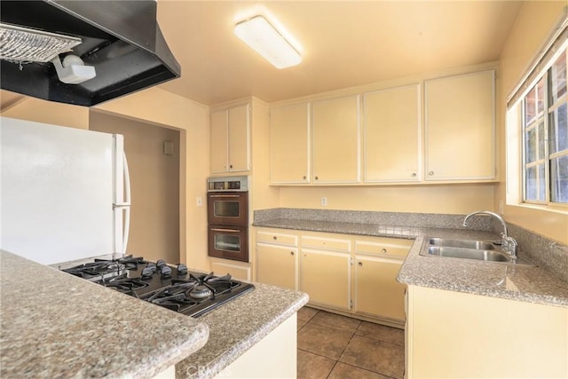 kitchen with black gas cooktop, a sink, light countertops, ventilation hood, and freestanding refrigerator