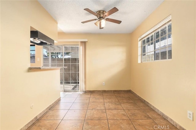 spare room with a ceiling fan, a textured ceiling, baseboards, and light tile patterned floors