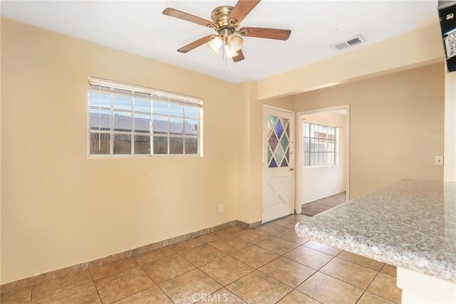 spare room with light tile patterned floors, baseboards, visible vents, and a ceiling fan