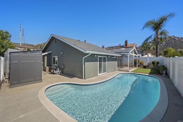 view of swimming pool with an outbuilding, a patio, a fenced backyard, a storage shed, and a fenced in pool