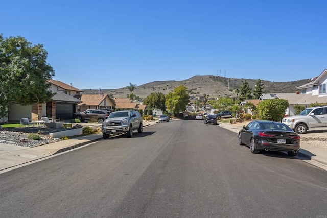 view of street with curbs, a residential view, a mountain view, and sidewalks