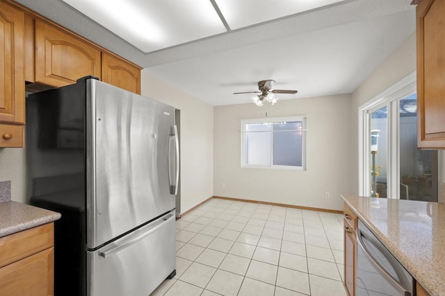 kitchen featuring appliances with stainless steel finishes, light tile patterned flooring, a ceiling fan, and baseboards