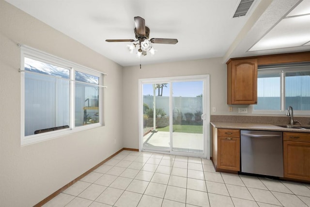 kitchen featuring light countertops, stainless steel dishwasher, brown cabinetry, a sink, and baseboards