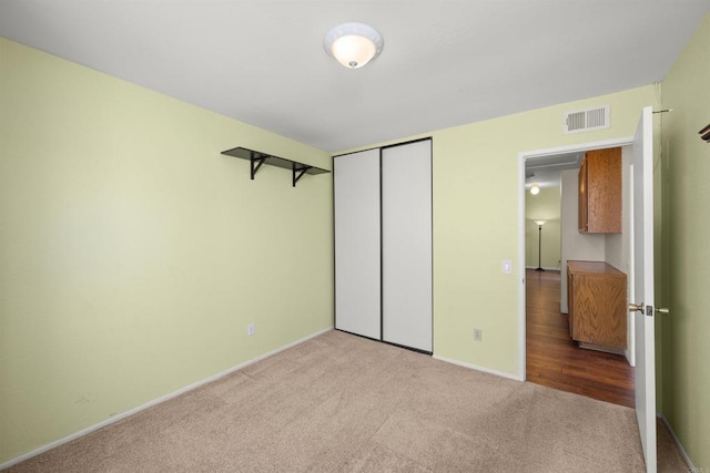 unfurnished bedroom with a closet, carpet flooring, visible vents, and baseboards