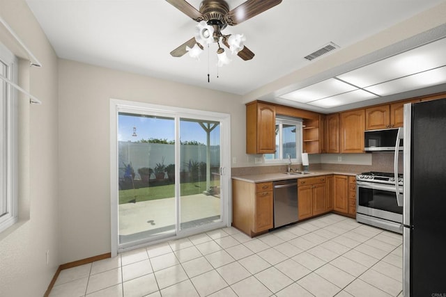 kitchen featuring stainless steel appliances, a sink, visible vents, light countertops, and brown cabinets