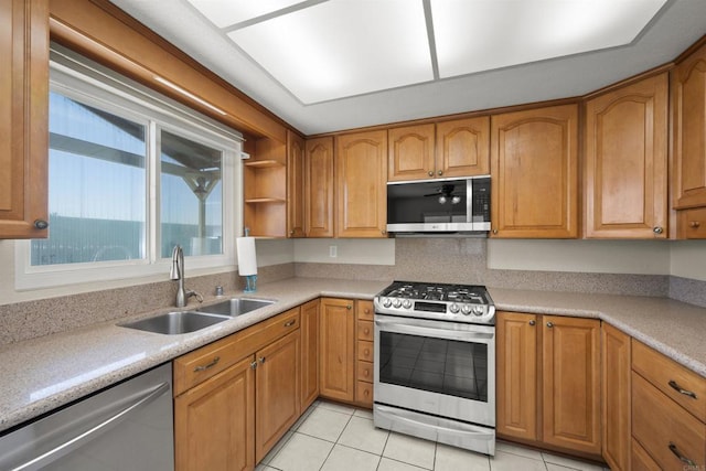 kitchen with stainless steel appliances, brown cabinetry, a sink, and light countertops