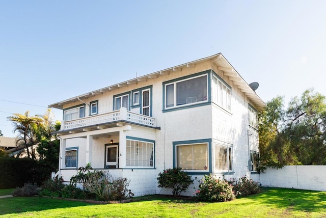 back of property featuring a lawn, a balcony, and fence