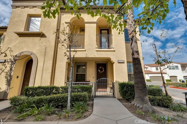 view of front of house featuring a balcony, a gate, and stucco siding