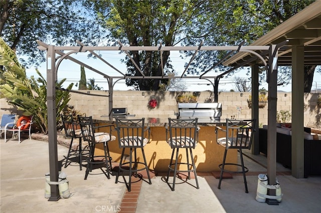 view of patio featuring outdoor dry bar, area for grilling, and fence