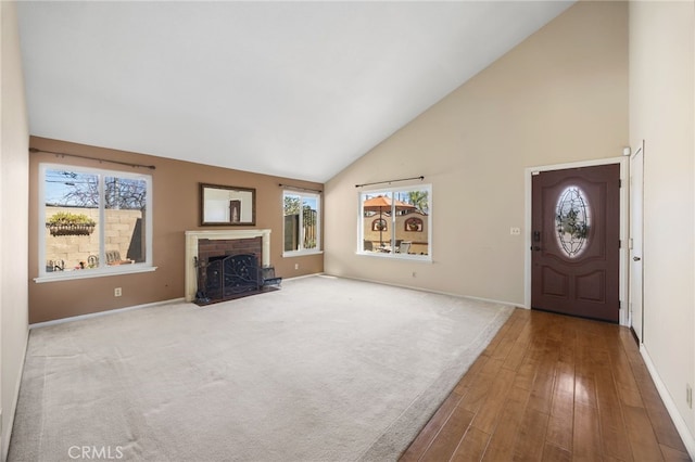 foyer featuring a brick fireplace, baseboards, high vaulted ceiling, and wood finished floors