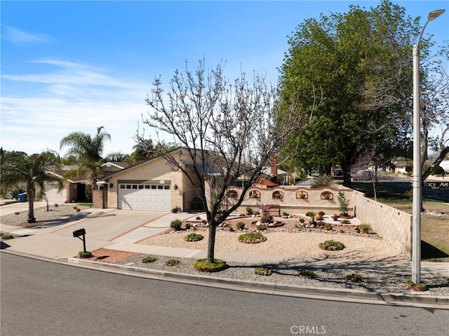 view of front of property with concrete driveway, an attached garage, fence, and stucco siding