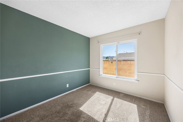 spare room featuring baseboards, a textured ceiling, and carpet flooring