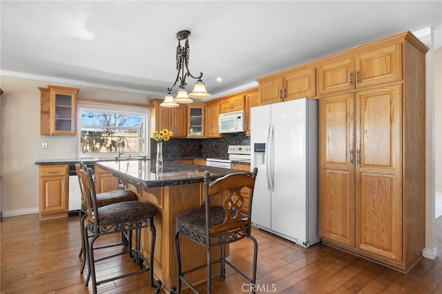 kitchen featuring white appliances, a kitchen bar, dark wood finished floors, and a center island