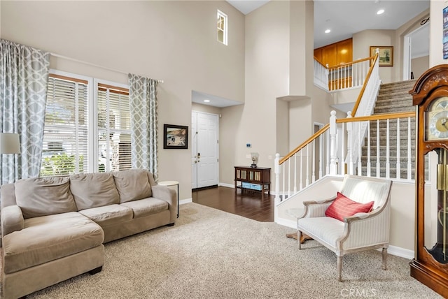 carpeted living area with recessed lighting, a towering ceiling, baseboards, and stairs