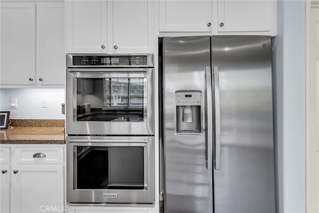 kitchen featuring appliances with stainless steel finishes, dark countertops, and white cabinetry