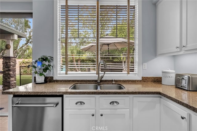 kitchen featuring stainless steel dishwasher, a toaster, white cabinets, and a sink