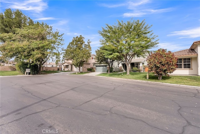 view of front of property with driveway, a tiled roof, a residential view, stucco siding, and a front lawn