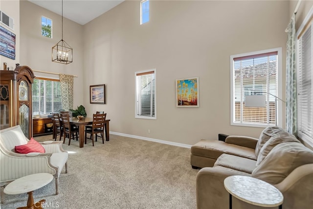 carpeted living room featuring a chandelier, a high ceiling, and baseboards