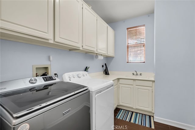 washroom with cabinet space, a sink, washer and clothes dryer, and baseboards