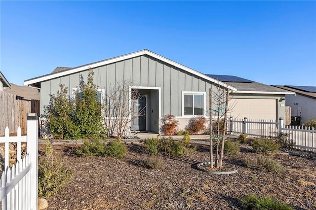 ranch-style home featuring board and batten siding, fence, a garage, and solar panels