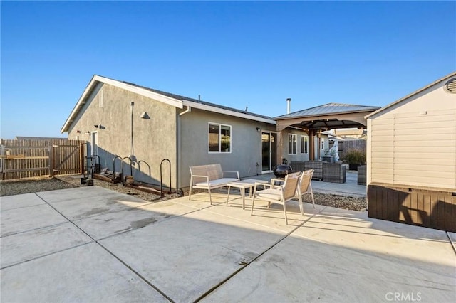 back of house with a patio, an outdoor hangout area, fence, a gazebo, and stucco siding