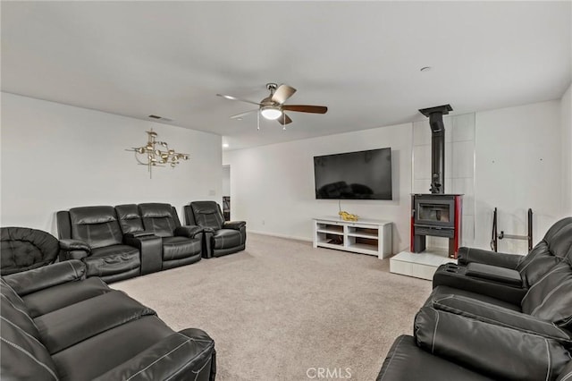 living room featuring visible vents, carpet, a wood stove, and a ceiling fan