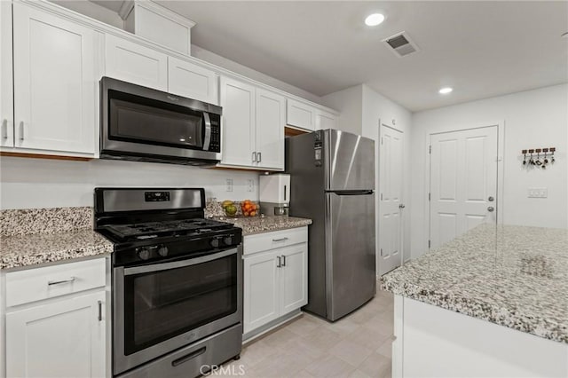 kitchen with stainless steel appliances, white cabinets, visible vents, and light stone counters