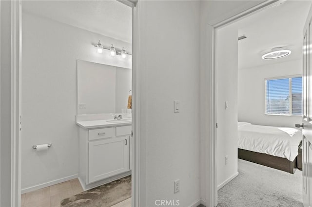 ensuite bathroom featuring baseboards, connected bathroom, and vanity