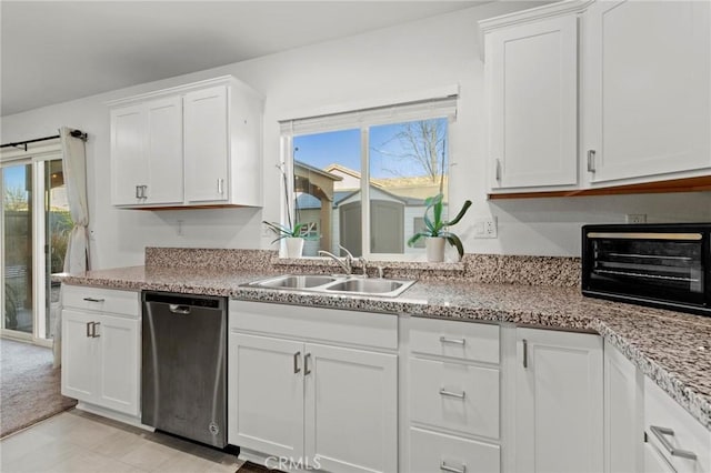 kitchen featuring a toaster, a sink, white cabinetry, stainless steel dishwasher, and light stone countertops